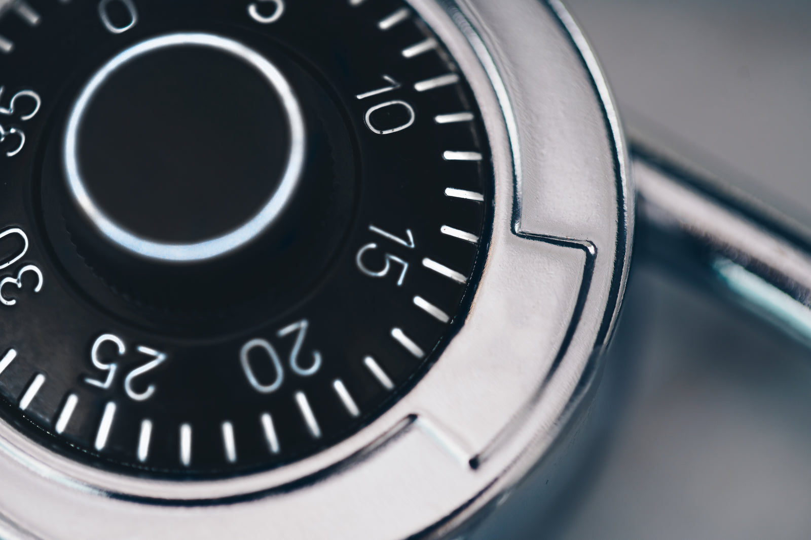Studio close-up of a brushed-metal combination lock with a sharply focused numbered dial